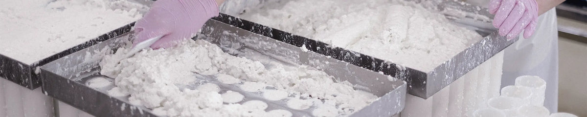 Worker in protective gloves handling curd in food manufacturing production